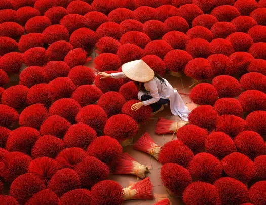 Person among bright red bundles of incense