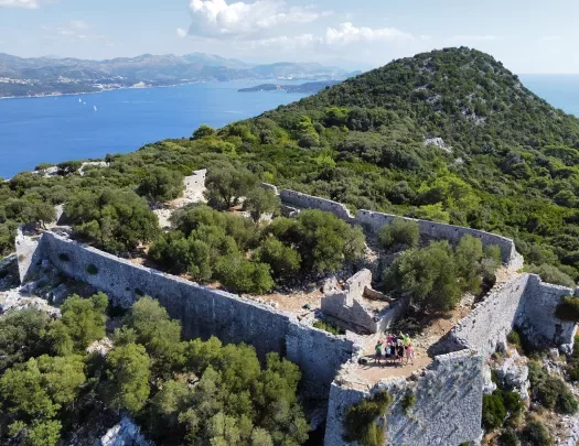 Bird's eye shot of guests among hilltop castle ruins.