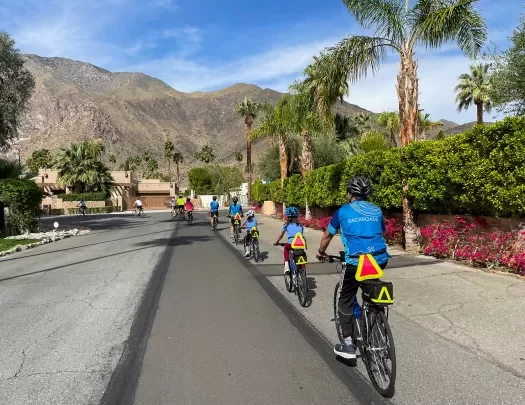 Group of guests riding single-file through a desert neighborhood.