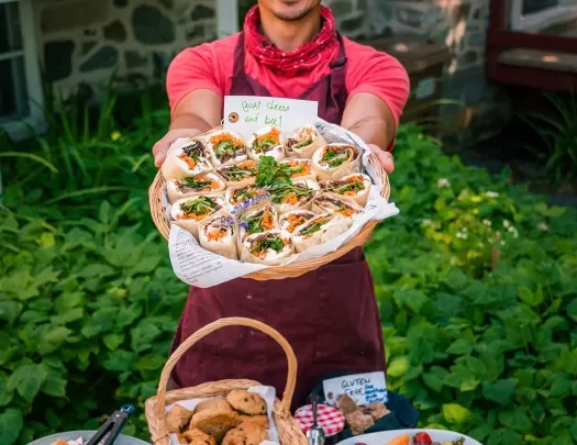 Man holding cheese and beet wrap-platter up towards camera.