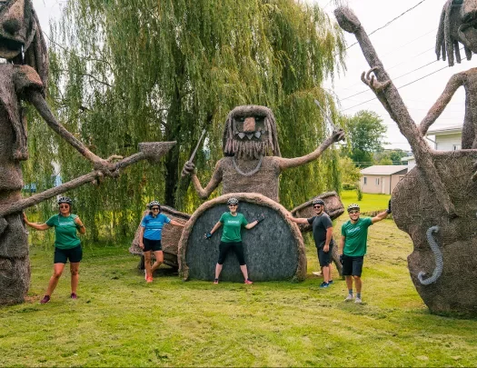 three guests posing with large wire and hay sculptures.