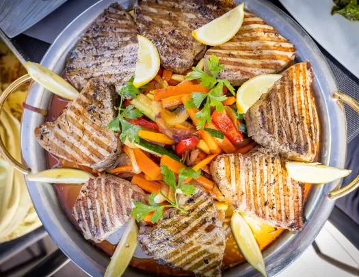 Platter of food, grilled meat, veggies, lemon slices, etc.