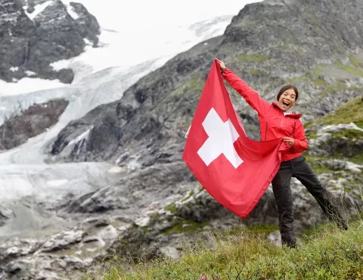 Guest/local on hillsides holding Swiss flag.