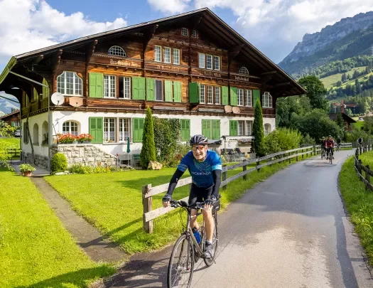 Guests cycling past wooden and stone hotel.