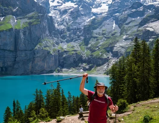 Guest raising pole in celebration, large mountains, lake in background. 