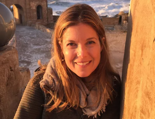 Close-up of guest during sunset, ocean, ruins behind them.