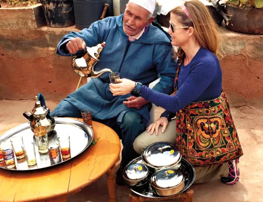 Guest with local, pouring tea.