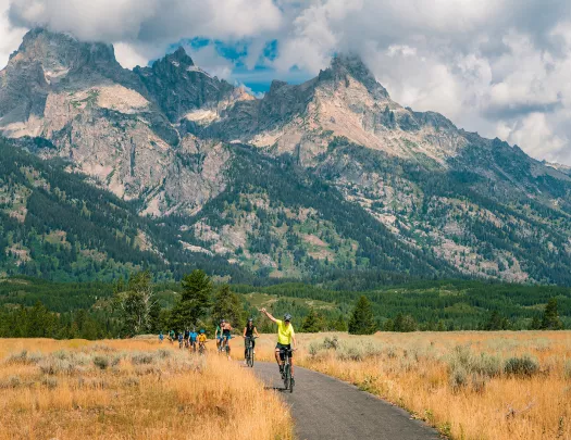 Backroads guests riding through golden fields and rocky mountains