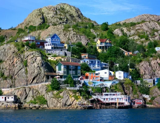 Wide shot of colorful coastal town in hillside. water below.