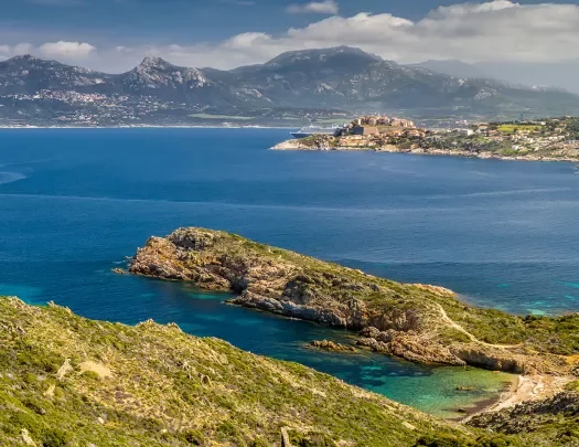 Wide shot of Italian lakeside, large peninsula, hills, coastal town in distance.