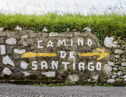 Shot of stone wall with "Camino de Santiago" painted on it.