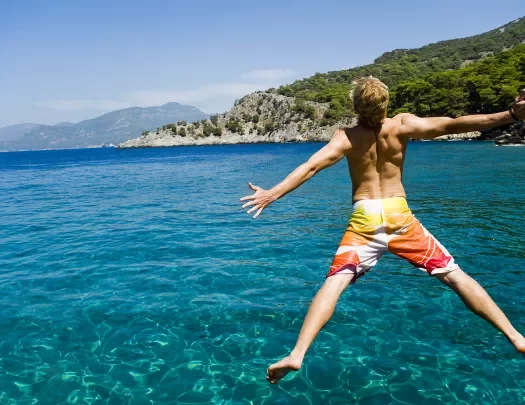 Guest jumping into ocean, coast in distance.