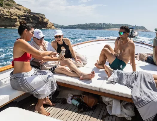 Six guests on boat, three looking at one of their phones.