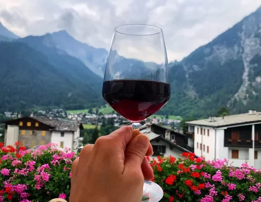 Point of view shot of a wine glass, mountain town, range in distance. 