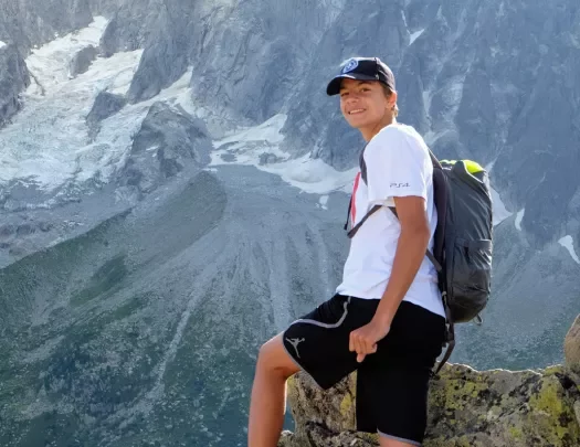 Young guest posing, mountain in the distance behind them.