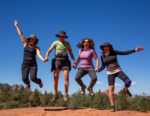 Four women jumping, posing for photo.