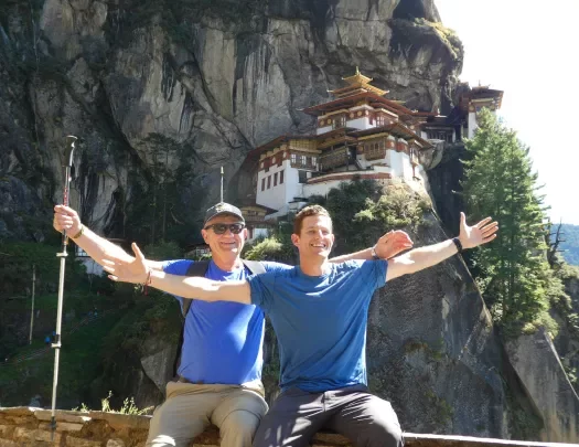 Two hikers posing with Tigers Nest in the background, Bhutan