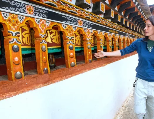 Woman running her hand over prayer wheels in Bhutan