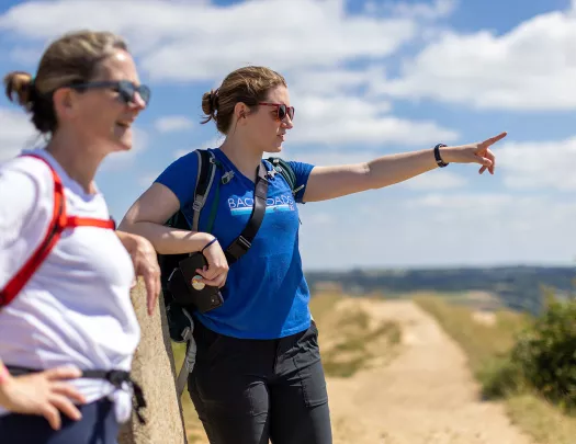 Two hikers on trail, pointing at view in the distance.