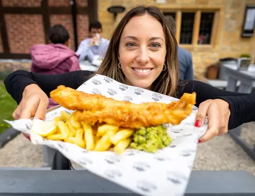 Backroads guest posing with fish and chips plate in England.