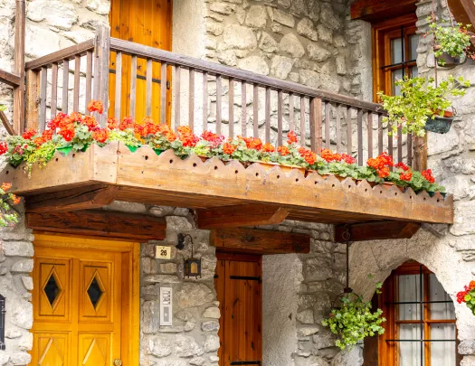 Housefront shot of stone building, wooden doors, balcony.