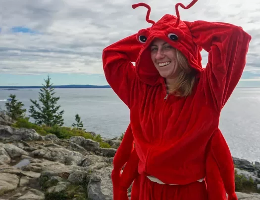 Guest/leader in lobster costume, large lake/ocean in background.