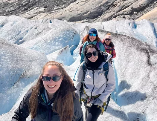 Four women hiking up a snow packed mountain trail.