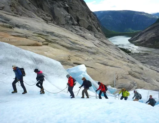 Hikers climbing an icy glacier in a single file line