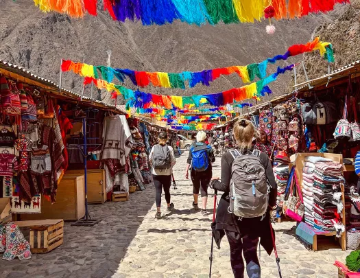 Guests walking through marketplace, colorful banners an mountain range above them.