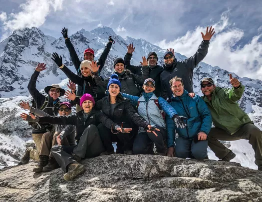 Group of guests on mountainside, all smiling, gesturing to camera.