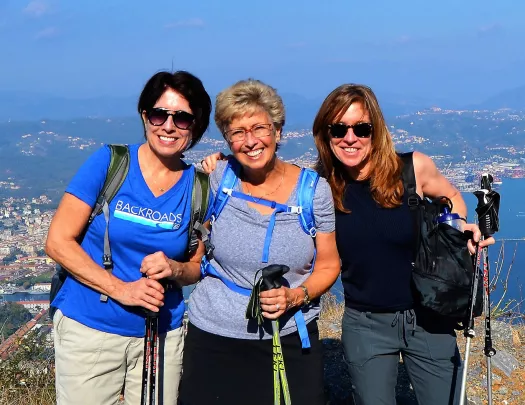 Three women posing together with Italian landscape behind them.