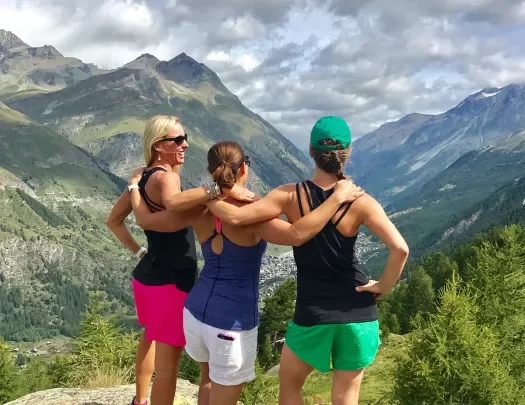 Three women hiking in in the Swiss Alps, looking over valley view.