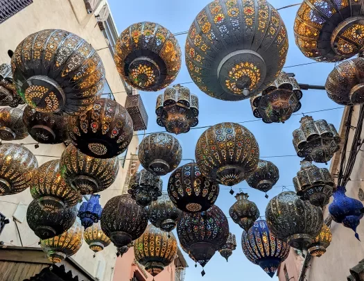 Intricate Moroccan lanterns hang above the street, strung between buildings