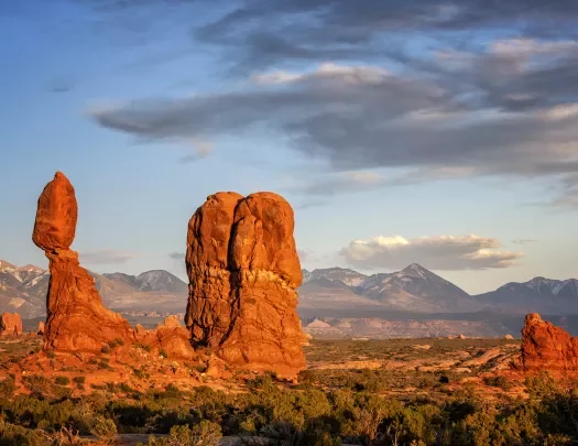 Stand-alone rock formation in desert at sunset