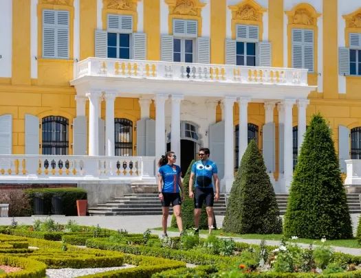 Man and woman in front of a yellow and white building at an outdoor garden