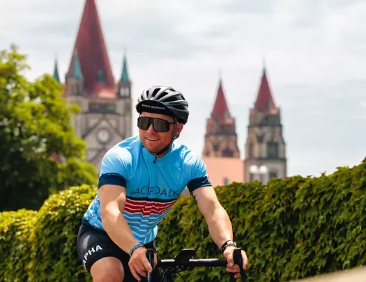 Man riding a bike and wearing sunglasses, with a clock tower in the distance