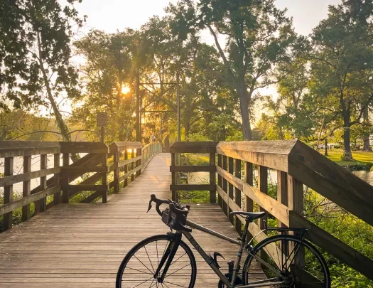 A bicycle leaning on a bridge during sunset