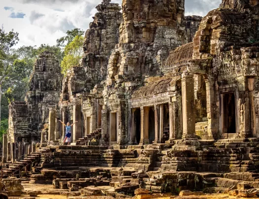 Woman with arms open next to ancient temple ruins