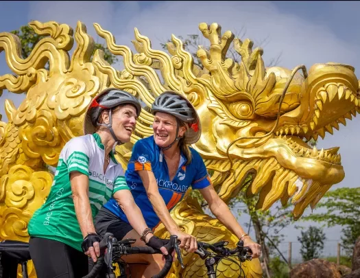 Women biking in front of a gold dragon statue