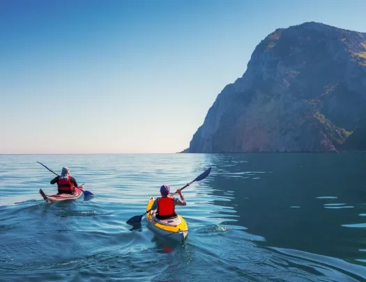 Two people paddling on kayaks in the middle of the ocean