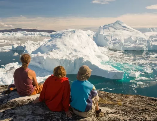 Three people look out at a sea of icebergs