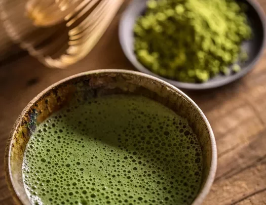 Cup of matcha tea next to a small plate of matcha powder