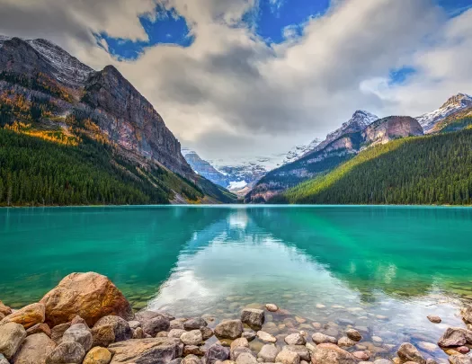 Open lake with large mountains and tall trees in the distance