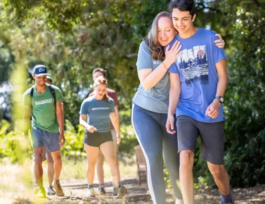 Woman hugging a man while walking on a gravel trail