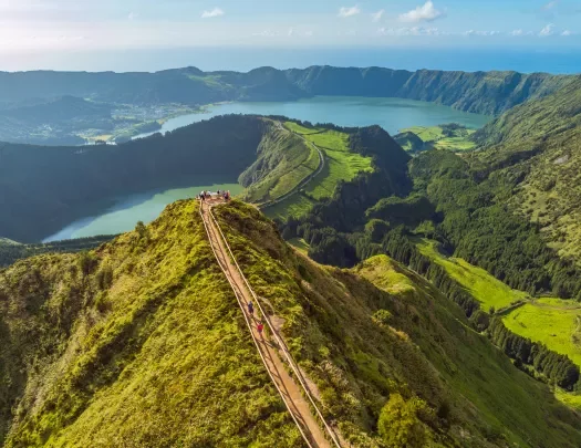 Sky view of a long path that sits on top of a long, grass-covered cliff