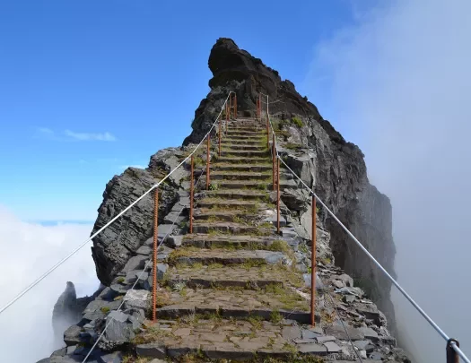 Stone stair way with metal railings leading towards the peak of a mountain