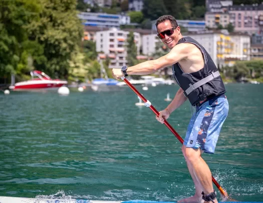 Man smiling while paddle boarding in a lake