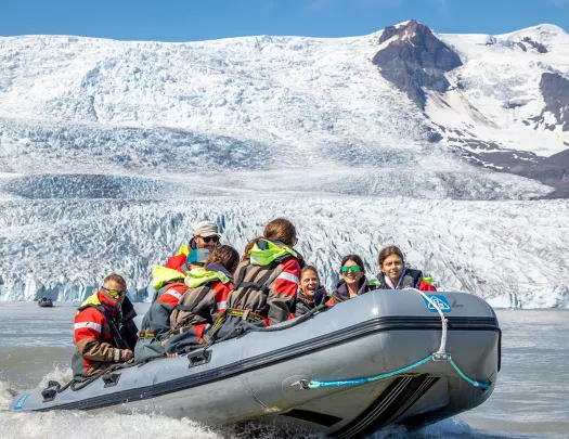 Group of people on a gray raft with snow mountains in the background