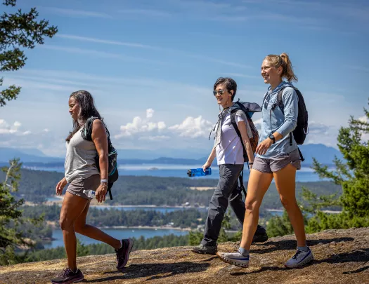 Group of three women hiking down a dirt path on a hill