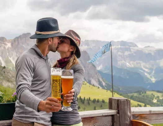 Man and woman kissing while holding up glasses of beer